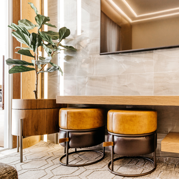 Modern eingerichteter Hotelbereich mit Sitzhockern, Tisch und Pflanze – Symbolbild für Hotelauflösung und Hotelräumung
